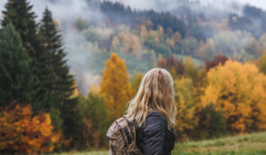Hiking in autumn forest. Woman during hike in mountain. Fog weat