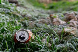 Discarded Red Drink Can on Grass with Blurred Background